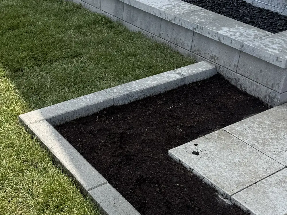 Bordure en blocs de béton délimitant une plate-bande le long d'une pelouse