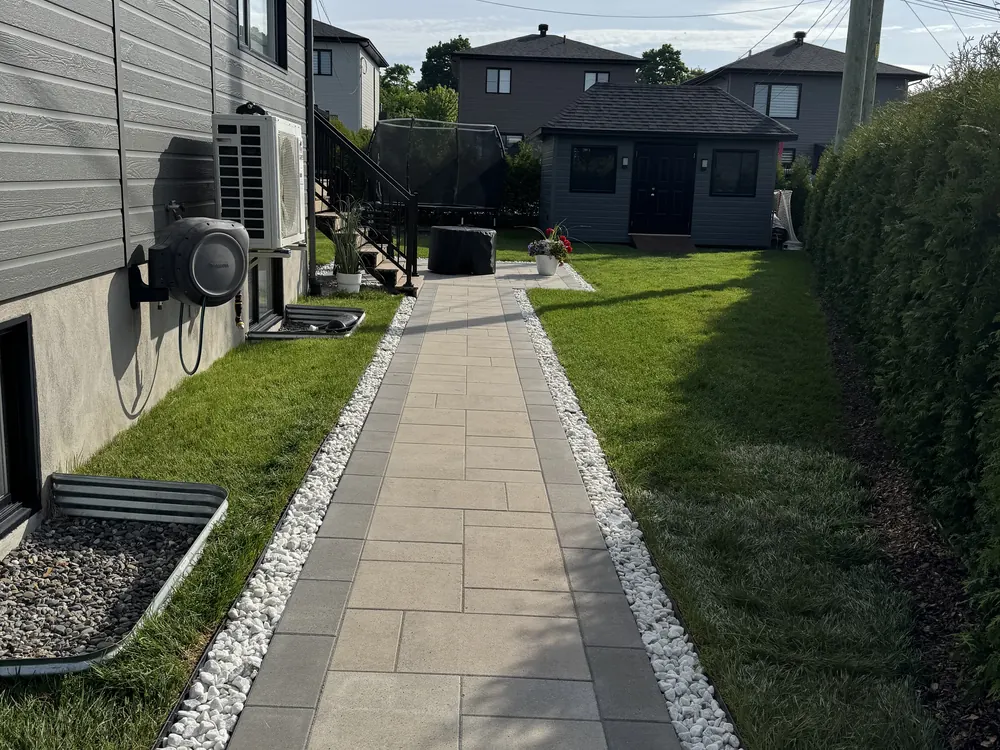Allée latérale en dalles de béton bordée de pierre blanche