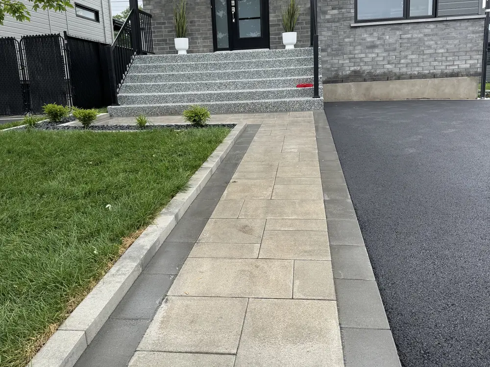 Allée en pavé uni bordée le long d'une entrée d'asphalte
