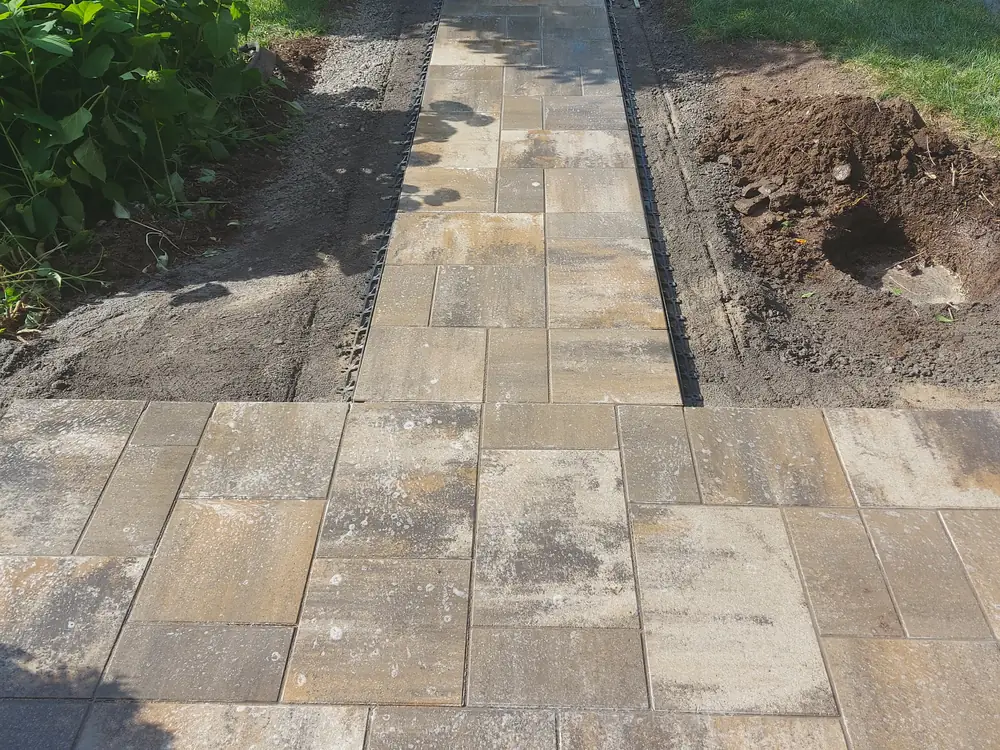 Trottoir en dalles grand format en cours de pose, avec bordures de retenue