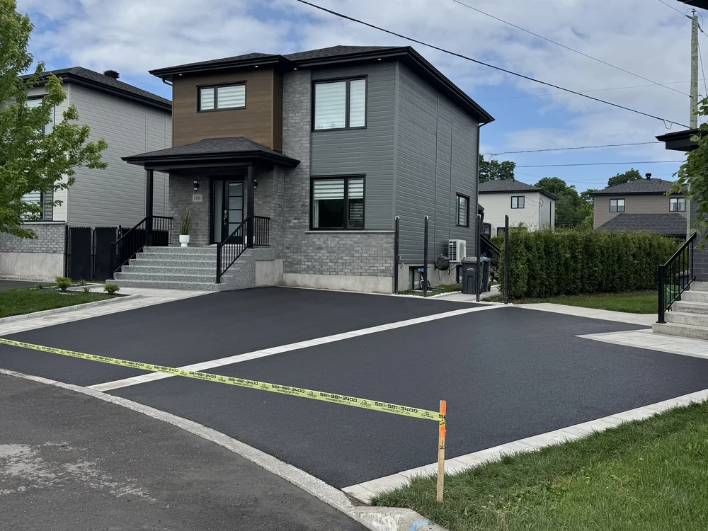 Entrée d'asphalte double avec bandes de pavé uni devant une résidence